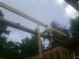 Carpenter setting a ridge beam over a new addition frame — Ice Dam Removal by Roofing Brothers in Ayer