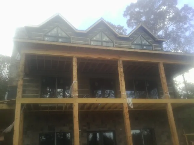 Dormers and porch framing on a large log home under construction — Roof Coating work by our crew in Ayer