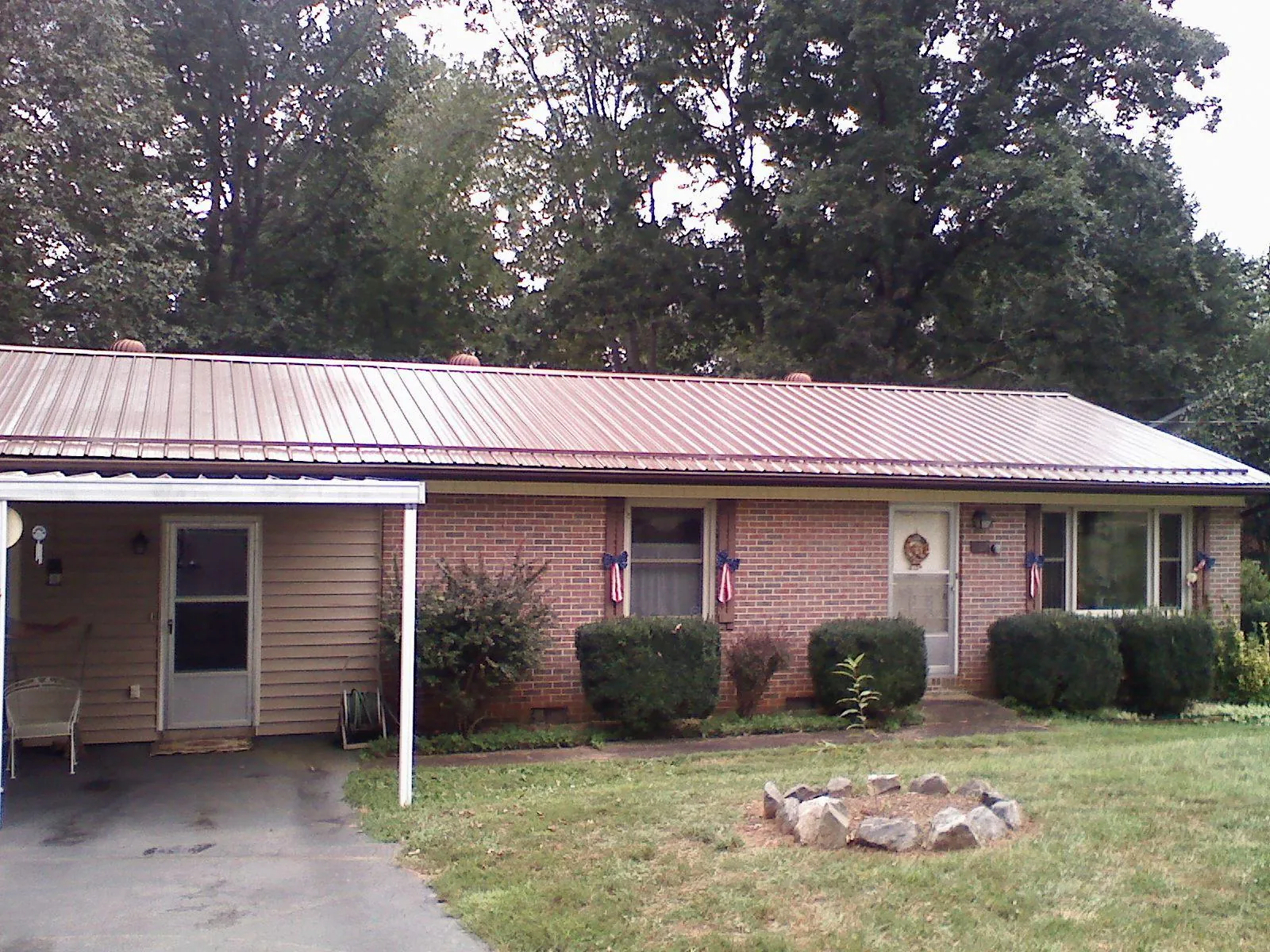 Bronze metal roof and carport on a brick ranch home — Roof Repair work by our crew in Ayer