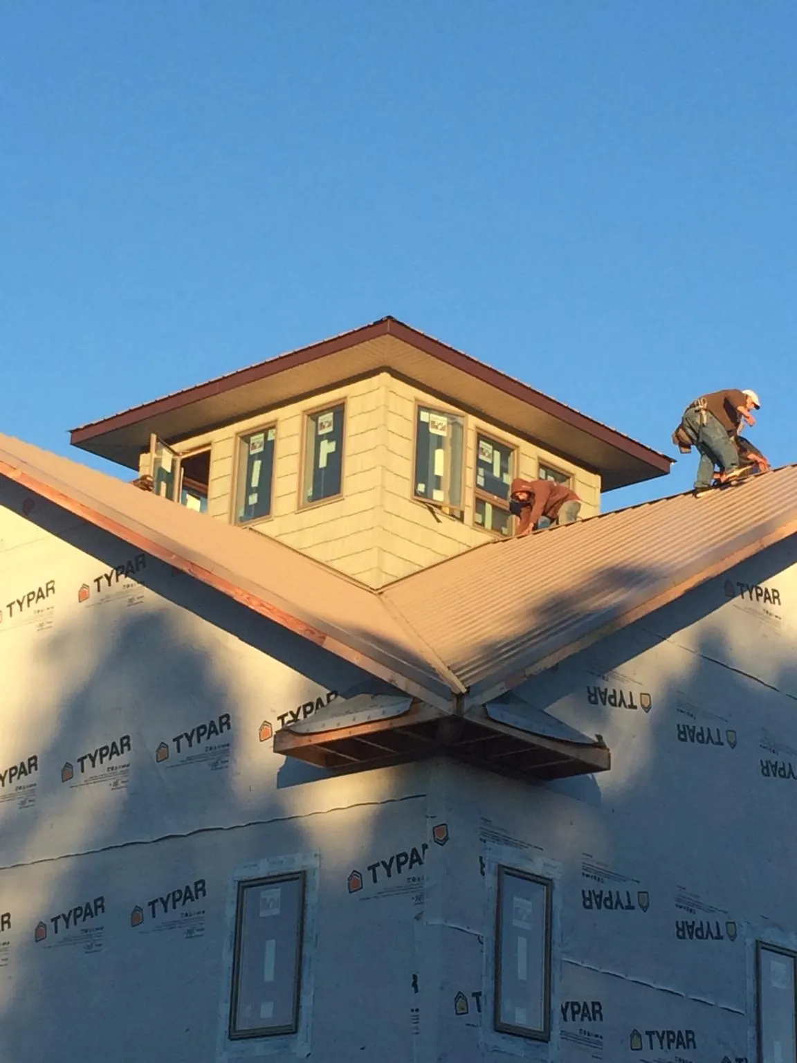 Roofers working around a rooftop cupola on a new metal roof at sunset — Roof Waterproofing in Ayer by Roofing Brothers